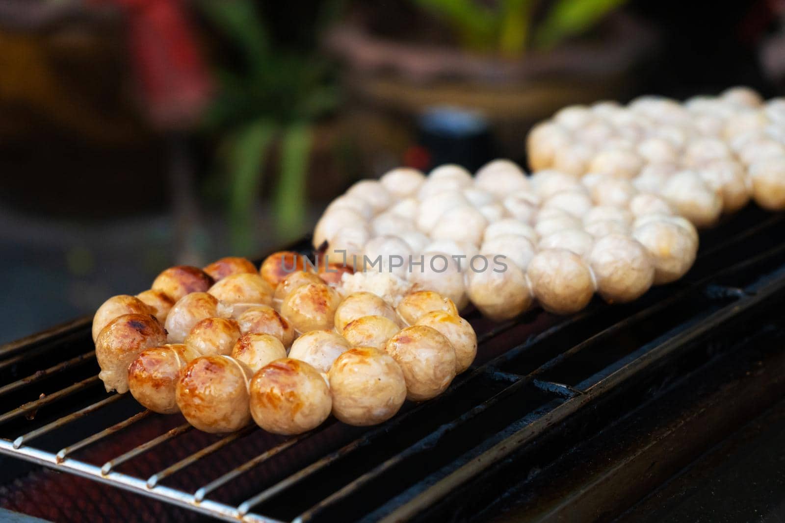 Meatballs are fried on an open-air stove at a street food market in Asia.