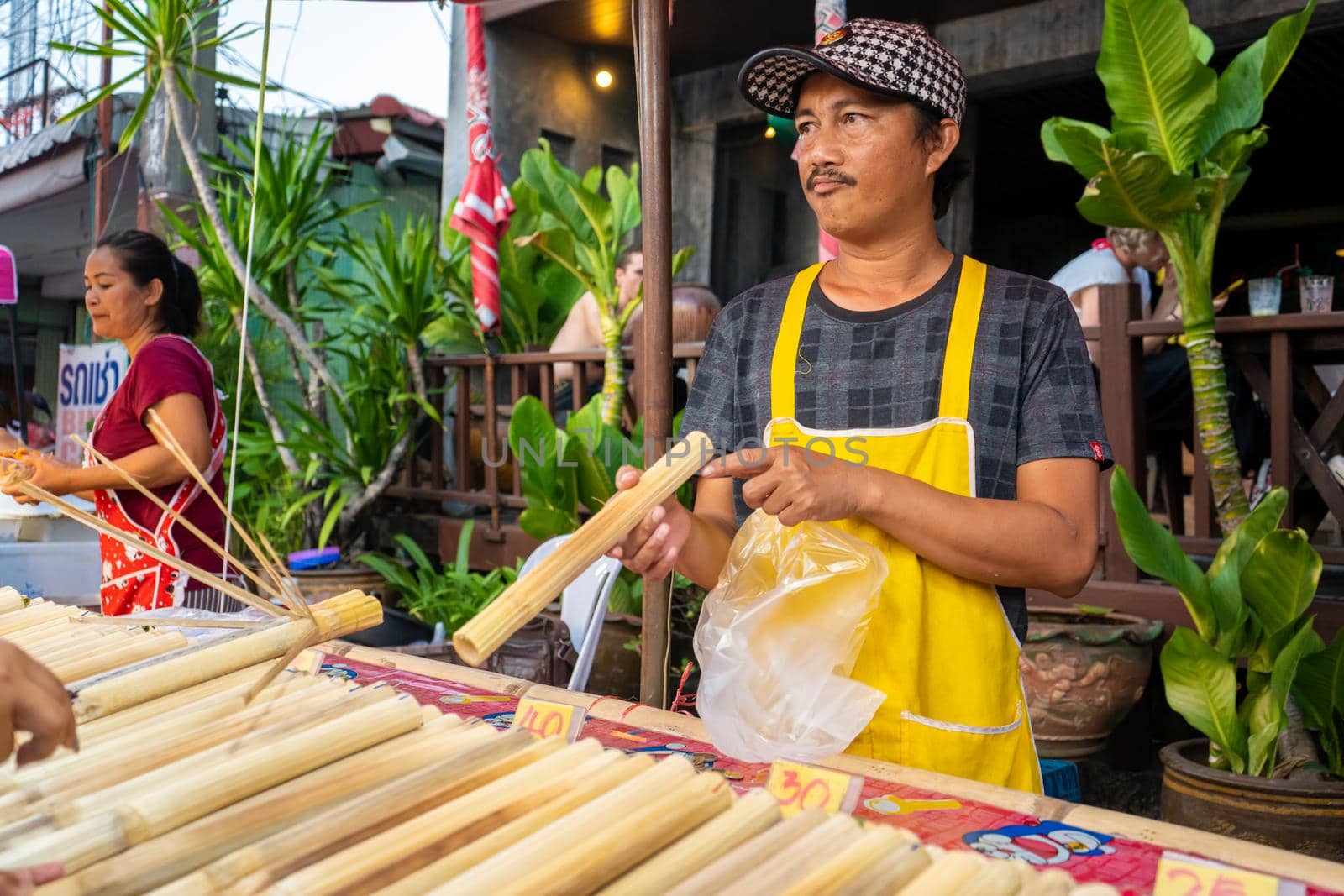 Street food market in Asia. A man sells rice in bamboo stalks.