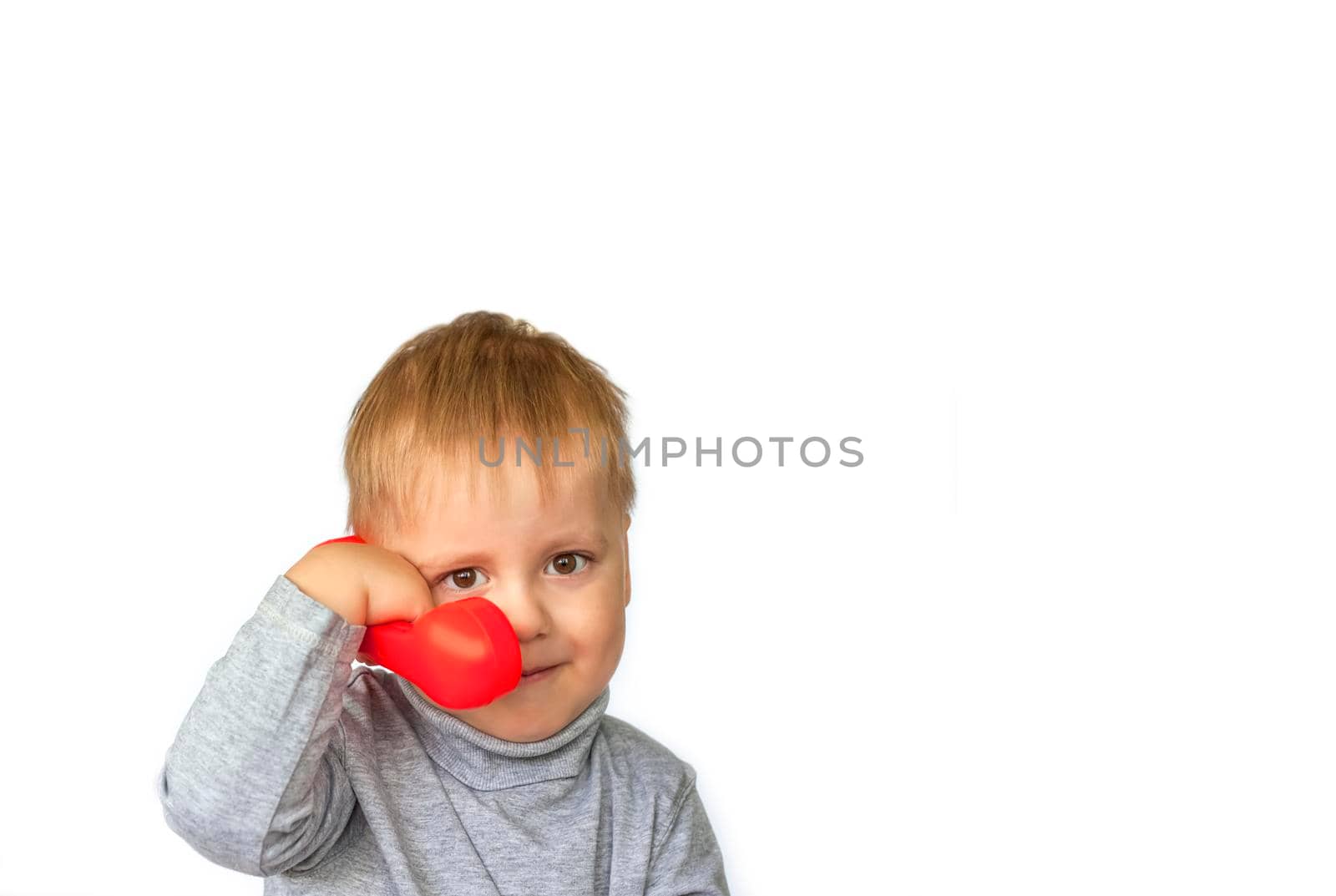 Portrait of an astonished cute little boy holding a red telephone receiver. Call here, call soon! The child is isolated on a white background. Concept for an advertising banner. 