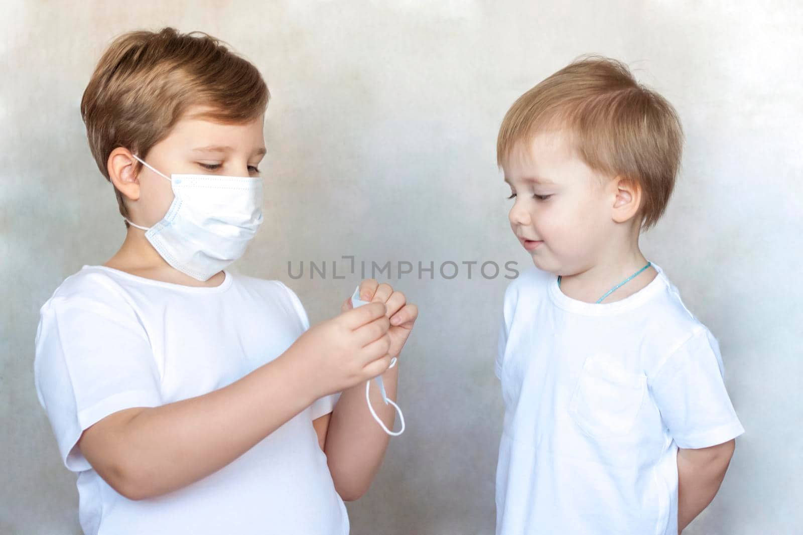 The older brother puts on a medical mask for his younger brother. Coronavirus, disease, infection, quarantine, medical mask, COVID-19. Quarantine and protection from influenza viruses and epidemics covid-19. Coronavirus quarantine.