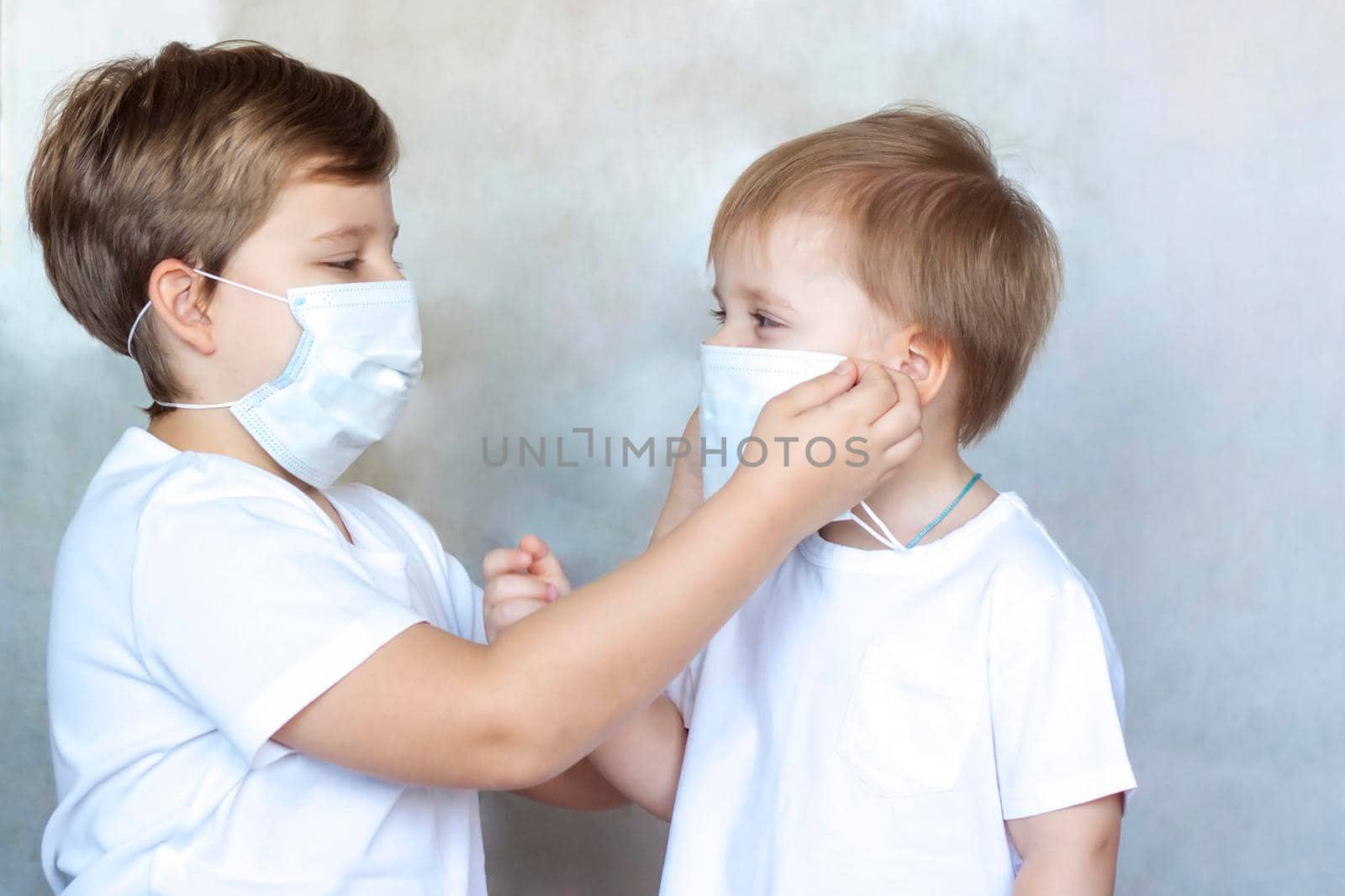 The older brother puts on a medical mask for his younger brother. Coronavirus, disease, infection, quarantine, medical mask, COVID-19. Quarantine and protection from influenza viruses and epidemics covid-19. Coronavirus quarantine.