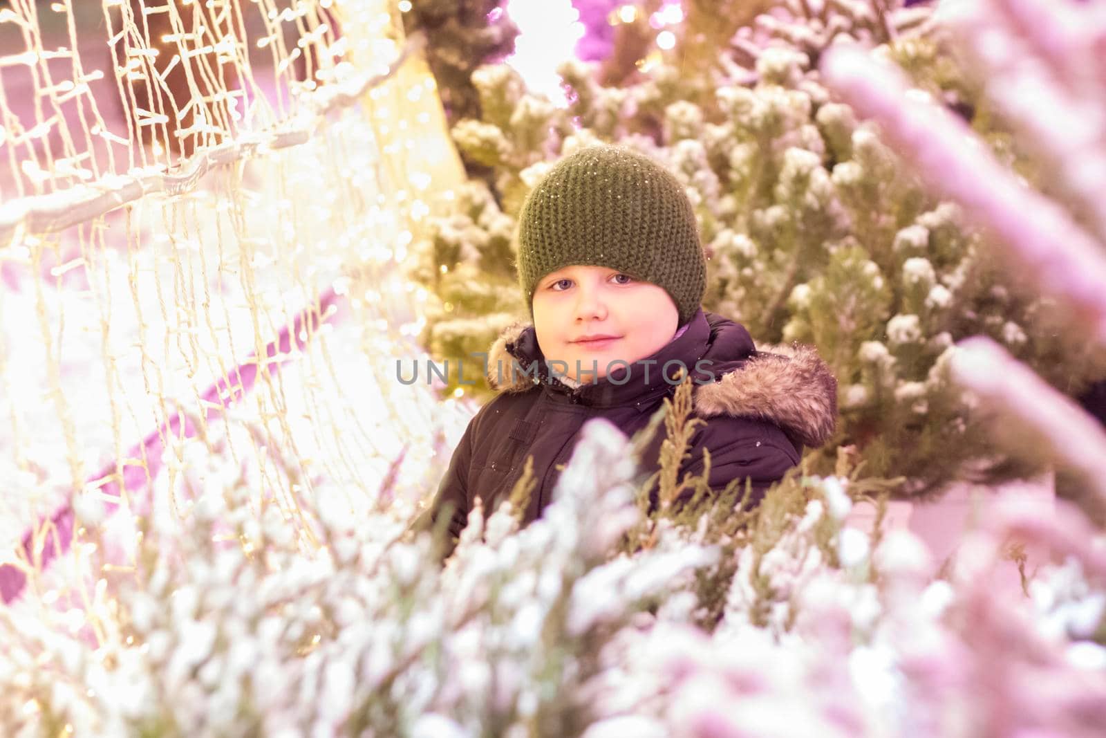 Portrait of a boy in the light of iridescent lights. Christmas in the city. illuminated decorations close-up. Photo