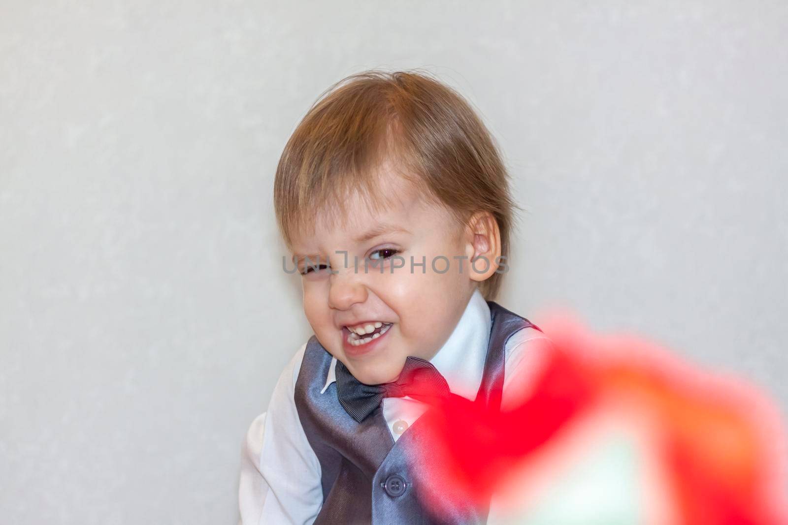 A little boy holds and hands over a red rose, the concept of the Valentine's Day theme. Portrait of a cute boy in a suit with a bow tie. Valentine's Day.