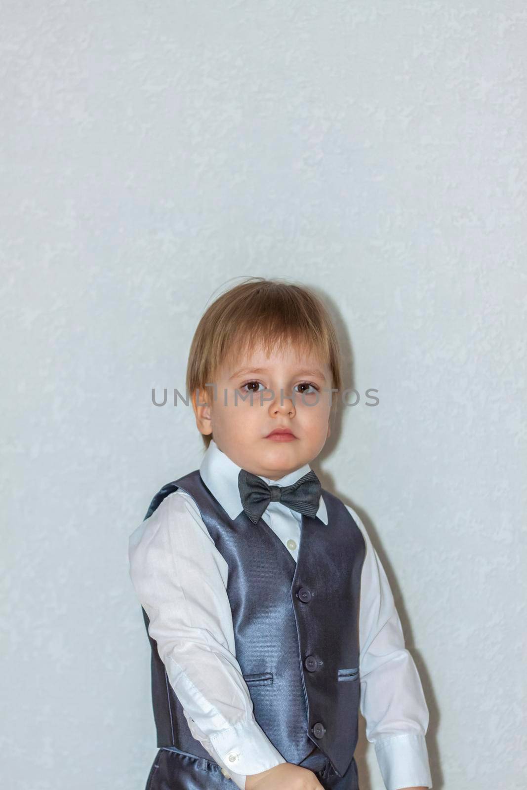 The concept of the Valentine's Day theme. Portrait of a cute boy in a suit with a bow tie. Valentine's Day.