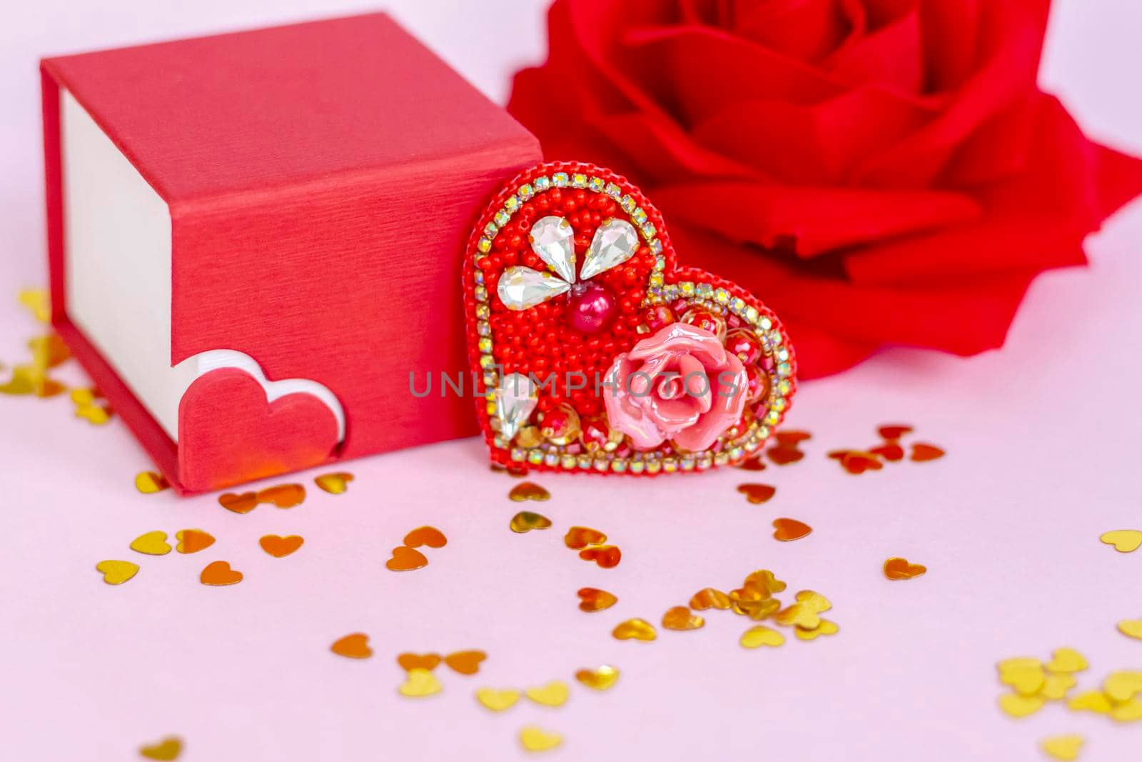 Pink background with gold hearts, sequins. Red heart made of beads. The concept of the Valentine's Day theme. Postcard, template, background for graphic works. The concept of the Valentine's Day theme. February 14