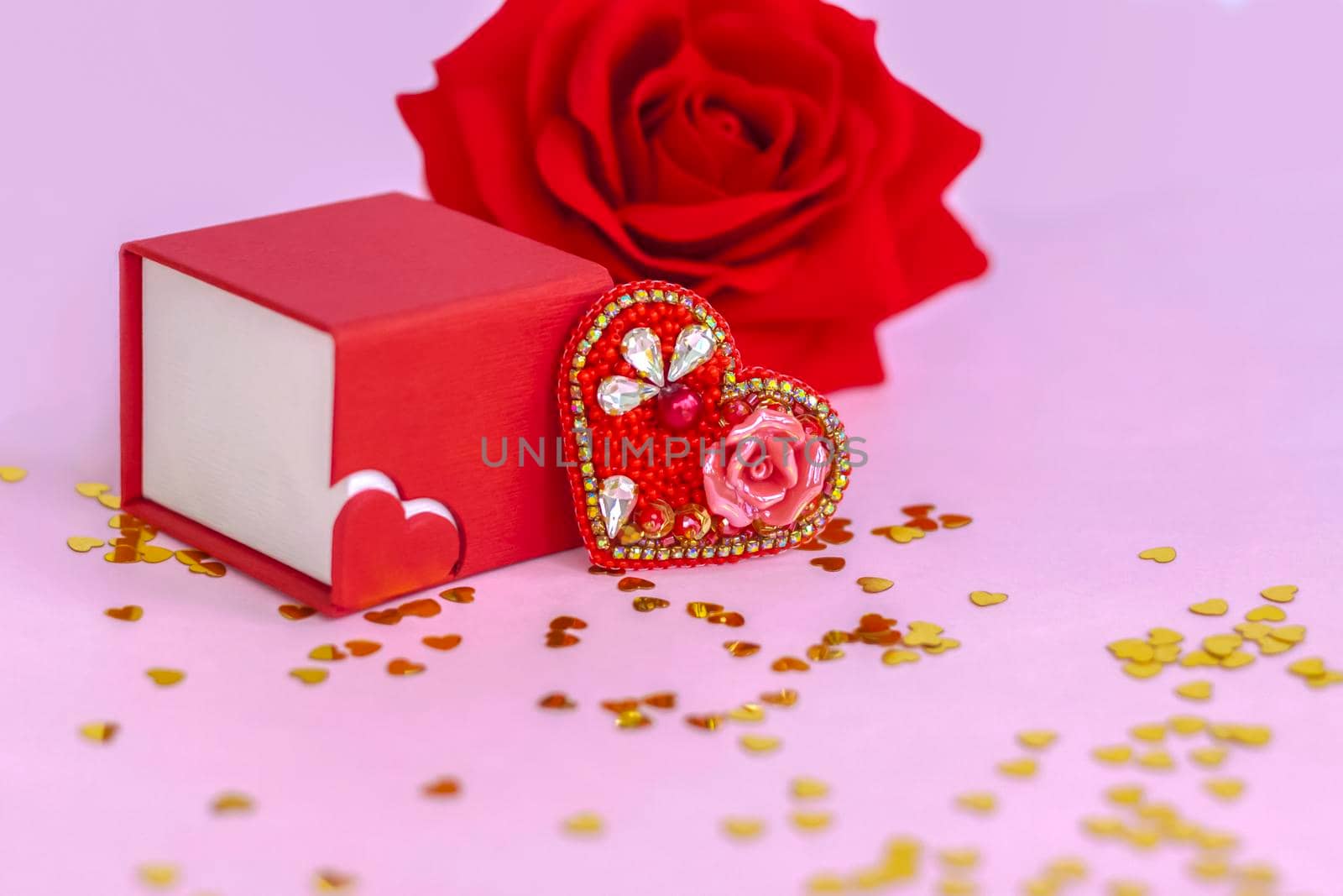 Pink background with gold hearts, sequins. Red heart made of beads. The concept of the Valentine's Day theme. Postcard, template, background for graphic works. The concept of the Valentine's Day theme. February 14