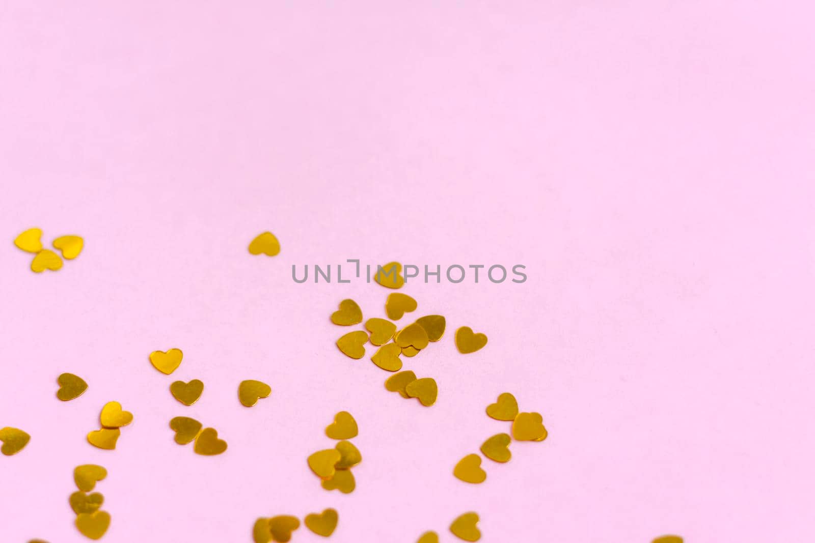 Pink background with gold hearts, sequins. The concept of the Valentine's Day theme. Postcard, template, background for graphic works