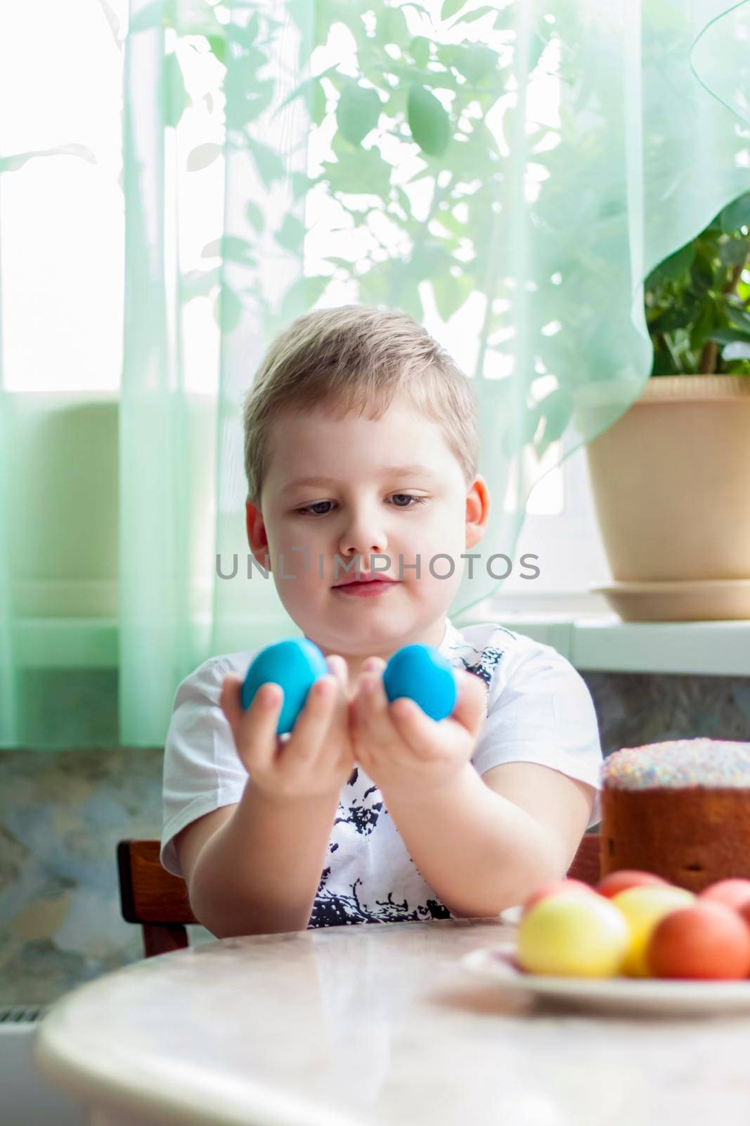 Portrait of a cute child with Easter eggs. Easter lunch. The feast of Holy Easter. Painted Easter eggs.