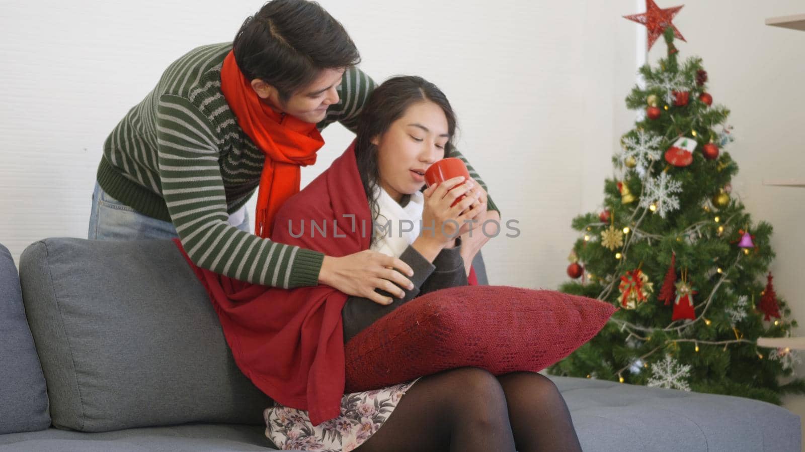 Loving man covering blanket to woman sit on sofa drink tea by Sorapop