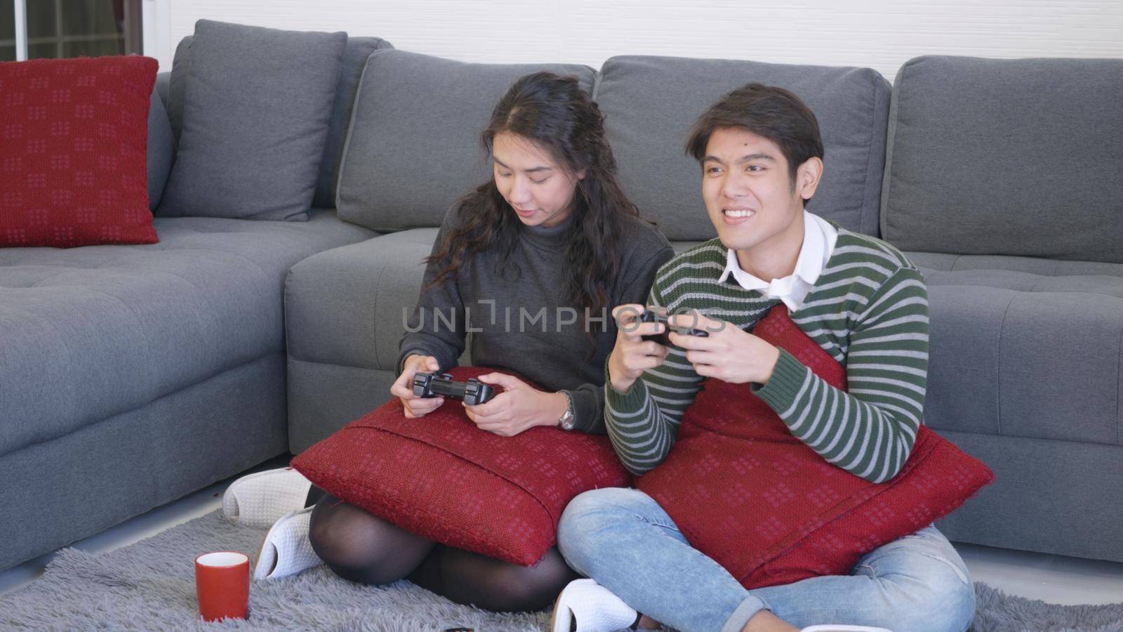 husband and wife smile and laugh enjoying funny with each other playing video game by Sorapop