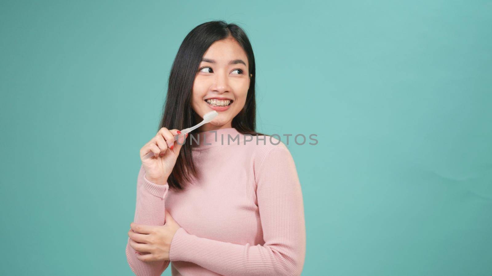 Asian young beautiful woman smile brushing teeth dancing enjoying music,  Female brush teeth singing song, dance and have fun isolated on blue background, lifestyle dental hygiene and health concept