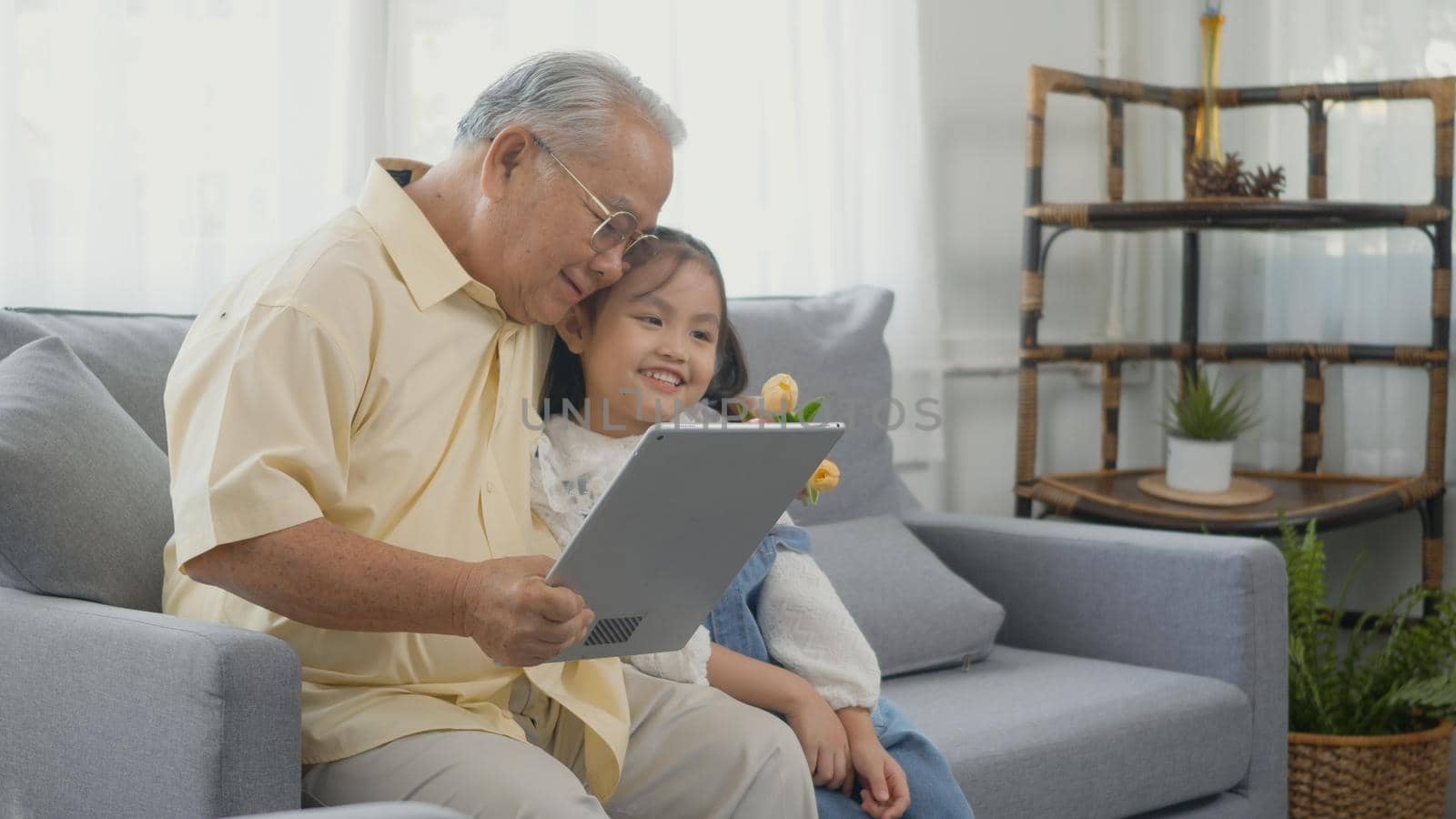 old man looking to tablet computer and granddaughter come visitor at home by Sorapop