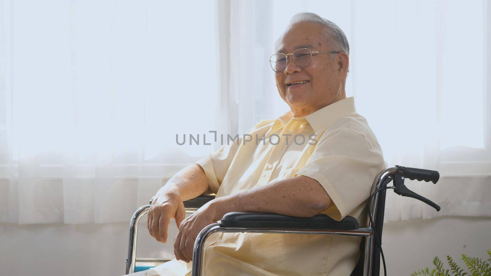 happy face senior old man sitting in wheelchair smiling in nursing home by Sorapop