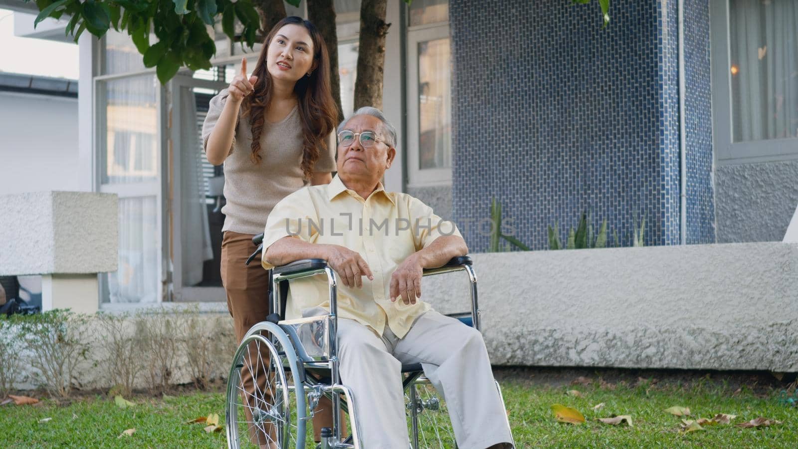 Disabled senior man on wheelchair with daughter in park by Sorapop