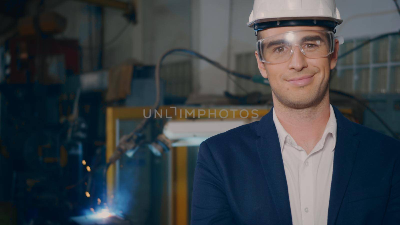 Professional confident engineer businessman in suits safety hats, goggles smile look at camera stand in heavy industrial facility manufacturing with steel welding from with fire spark