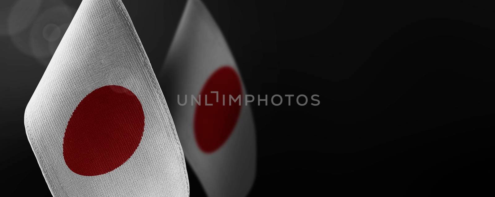 Small national flags of the Japan on a dark background.