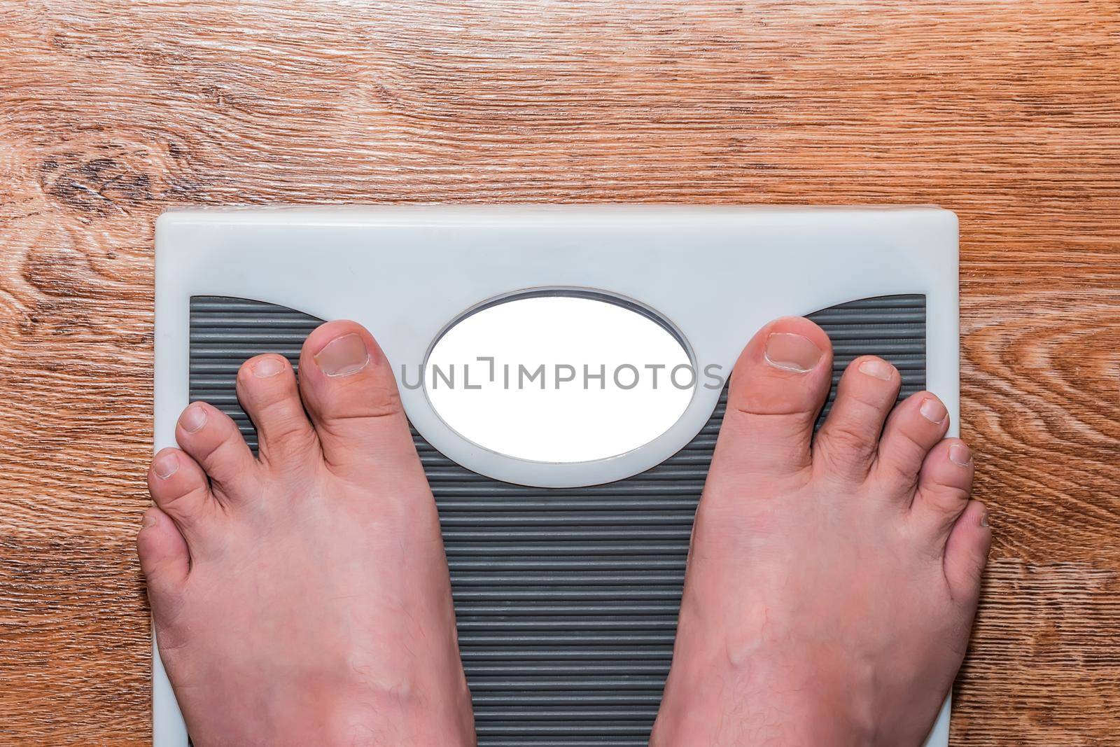 A man stands barefoot on a floor scale and measures his weight