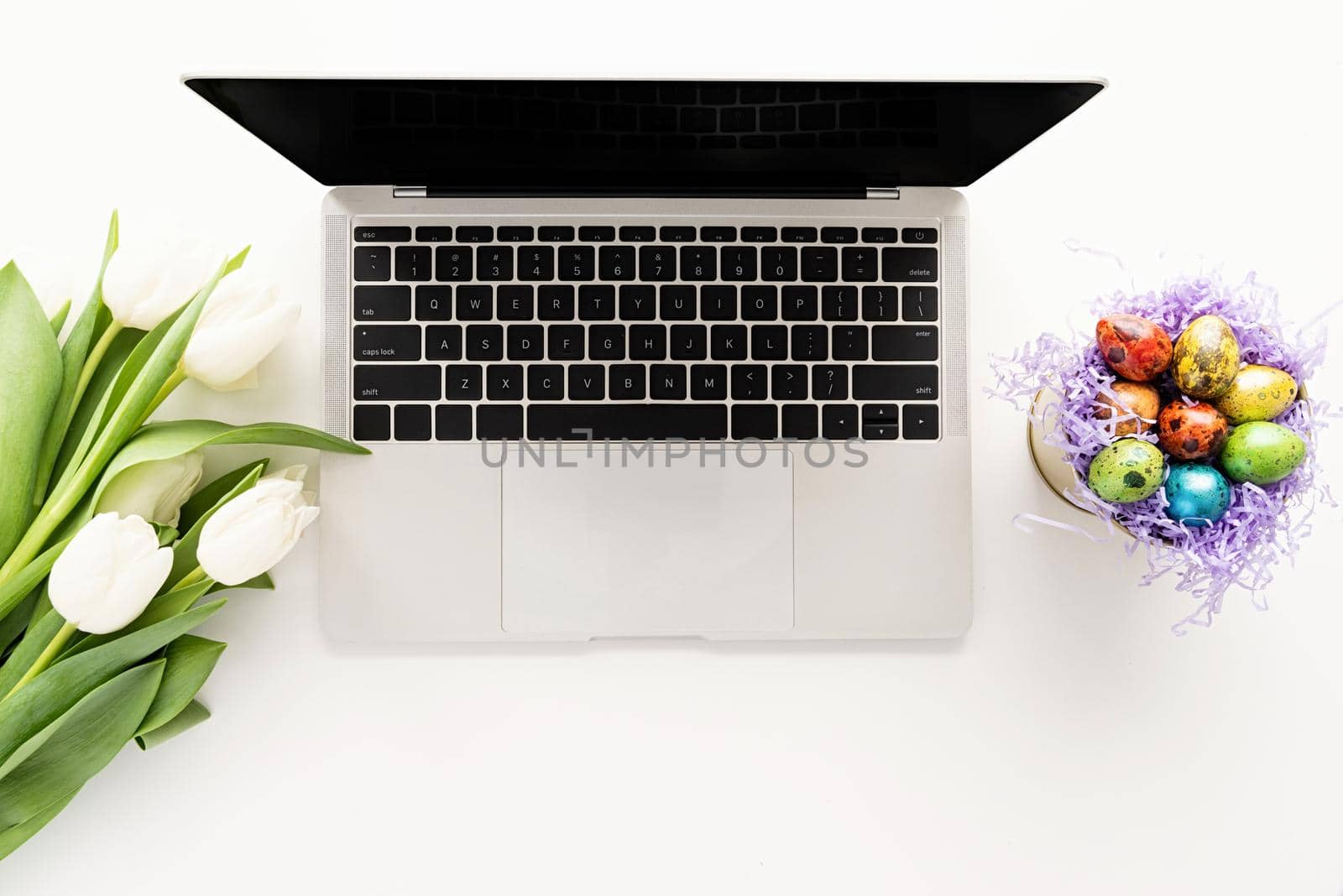 Women workspace mockup laptop computer, white tulip flowers and easter eggs in a bucket by Desperada