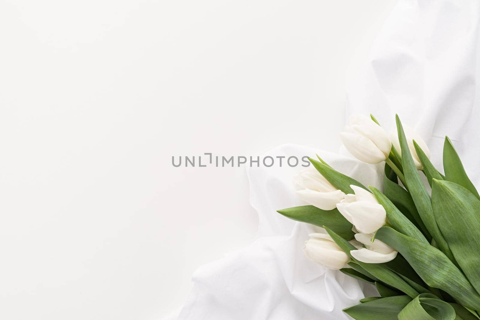 Spring concept. White tulip bouquet and fabric for mock up design on white background with copy space