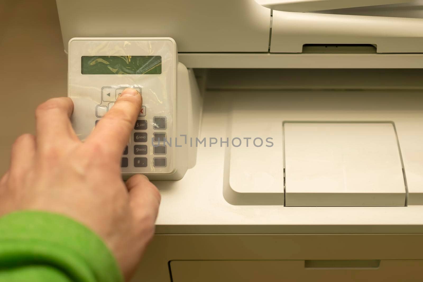 the hand of a person, an office worker, presses the buttons on the control panel of a printer, copier, or multifunction device