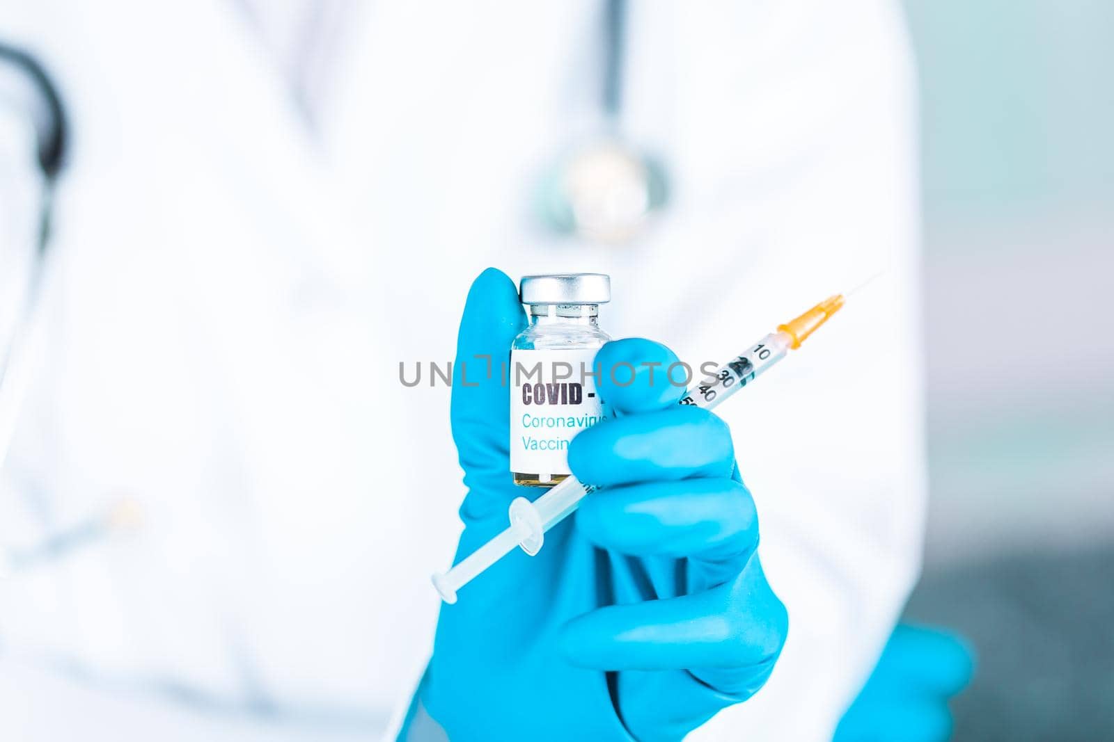 Woman doctor or nurse in uniform and gloves wearing face mask protective in lab, holding medicine vial vaccine bottle with COVID-19 Coronovirus vaccine label