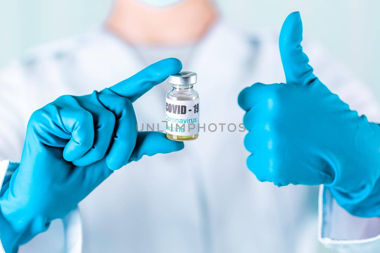 Woman doctor or nurse in uniform and gloves wearing face mask protective in lab, holding medicine vial vaccine bottle with COVID-19 Coronovirus vaccine label