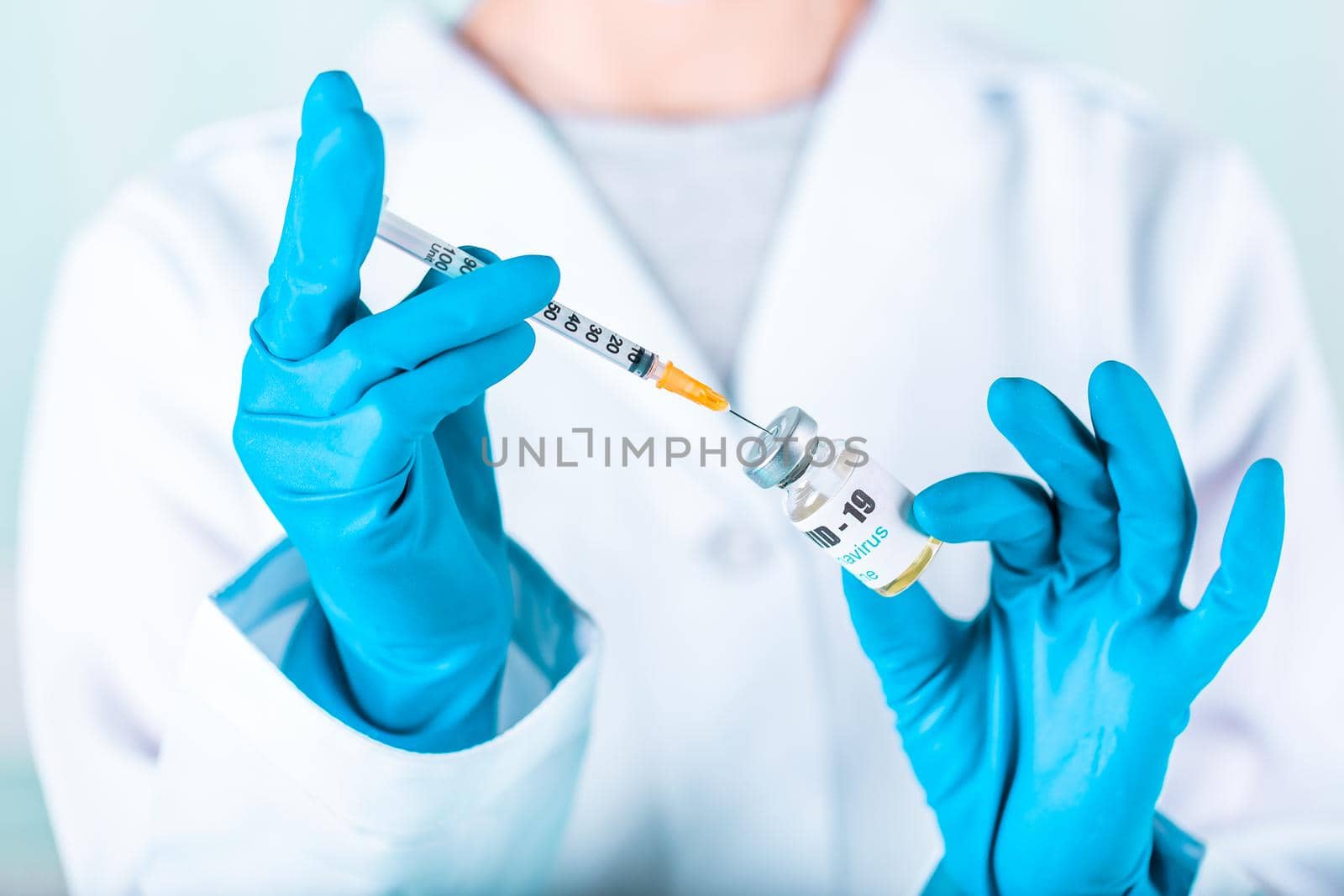 Woman doctor or nurse in uniform and gloves wearing face mask protective in lab, holding medicine vial vaccine bottle with COVID-19 Coronovirus vaccine label