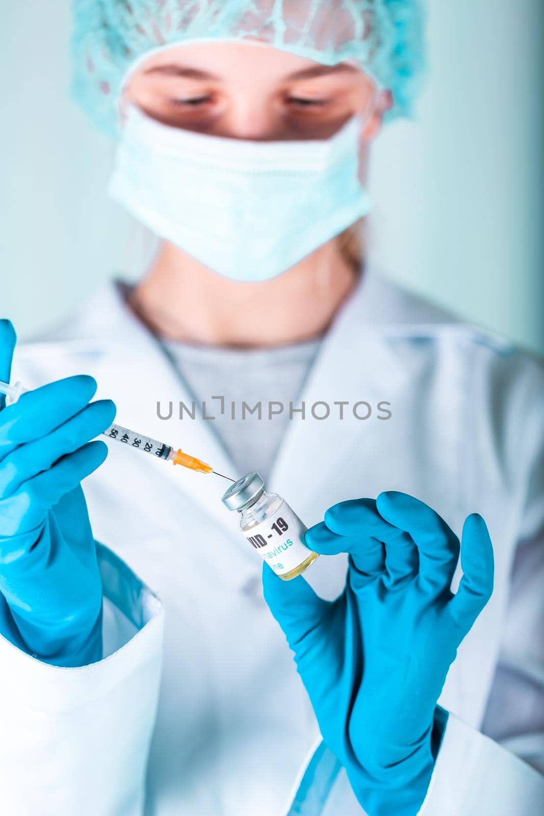 Woman doctor or nurse in uniform and gloves wearing face mask protective in lab, holding medicine vial vaccine bottle with COVID-19 Coronovirus vaccine label