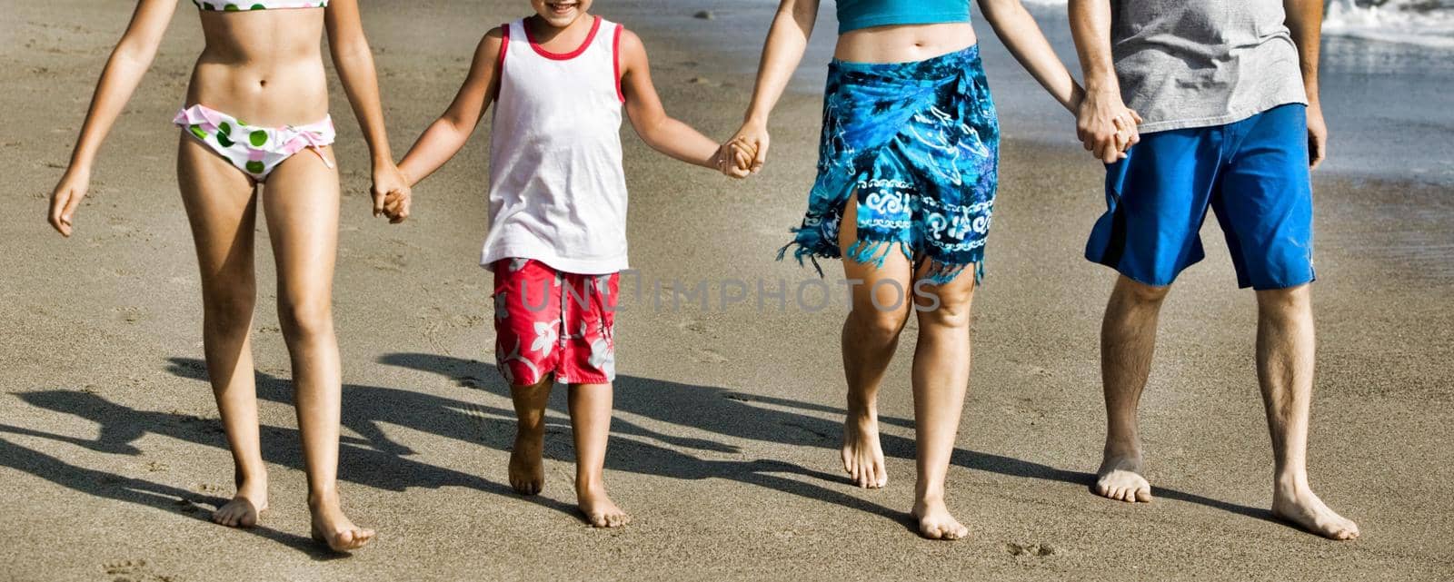 Cropped photo of family walking on the beach by moodboard