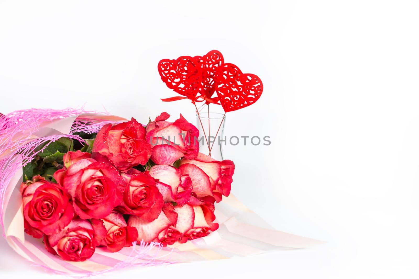Bouquet of red roses in a gift paper packaging vase with hearts. The concept of a gift to a woman for any event, a symbol of love, valentine's day