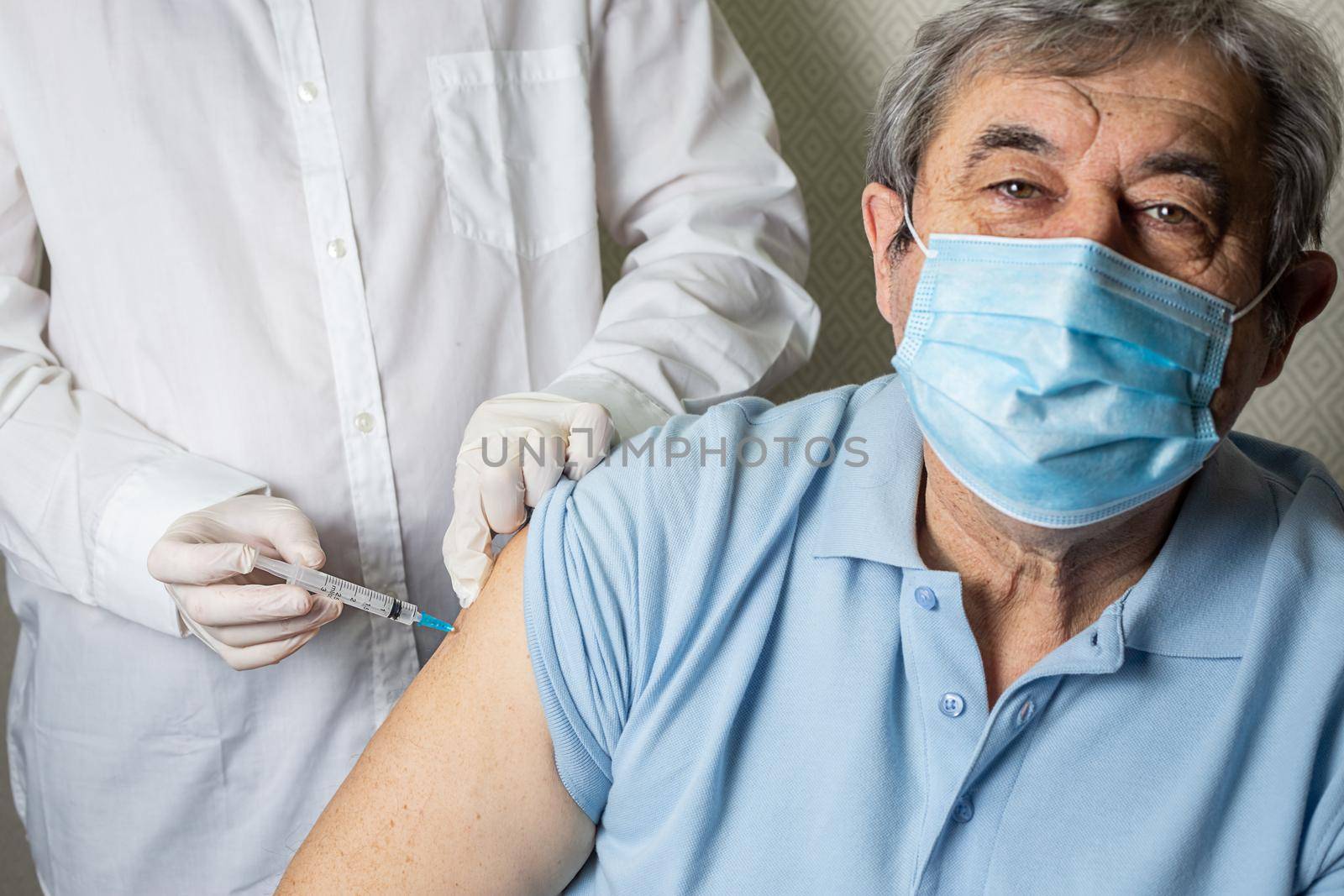 An elderly Caucasian man receives a dose of vaccination in a nursing home by galinasharapova