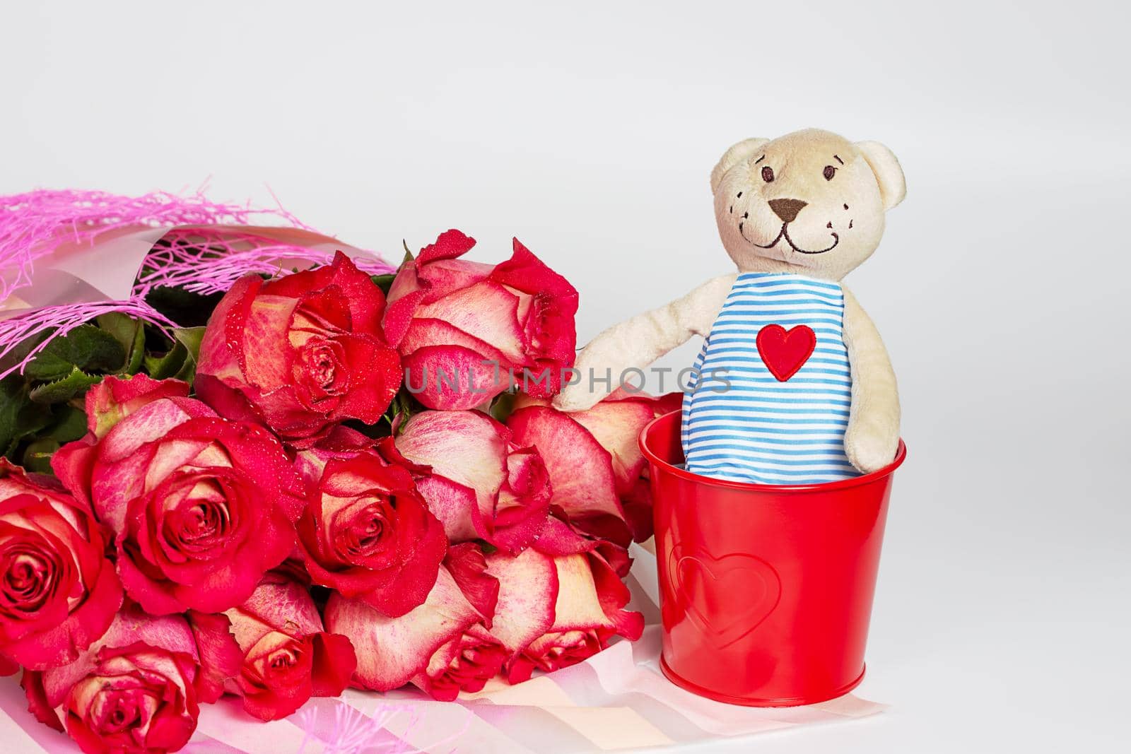 A bouquet of red roses in a gift paper package and a soft toy bear with by galinasharapova