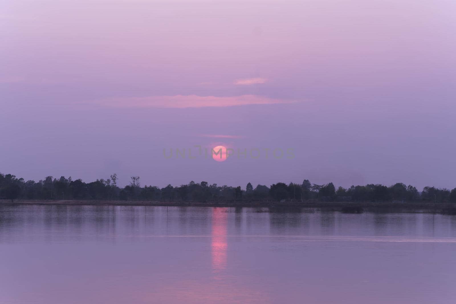 The scenery along the lake has an orange sky and a beautiful sunset.