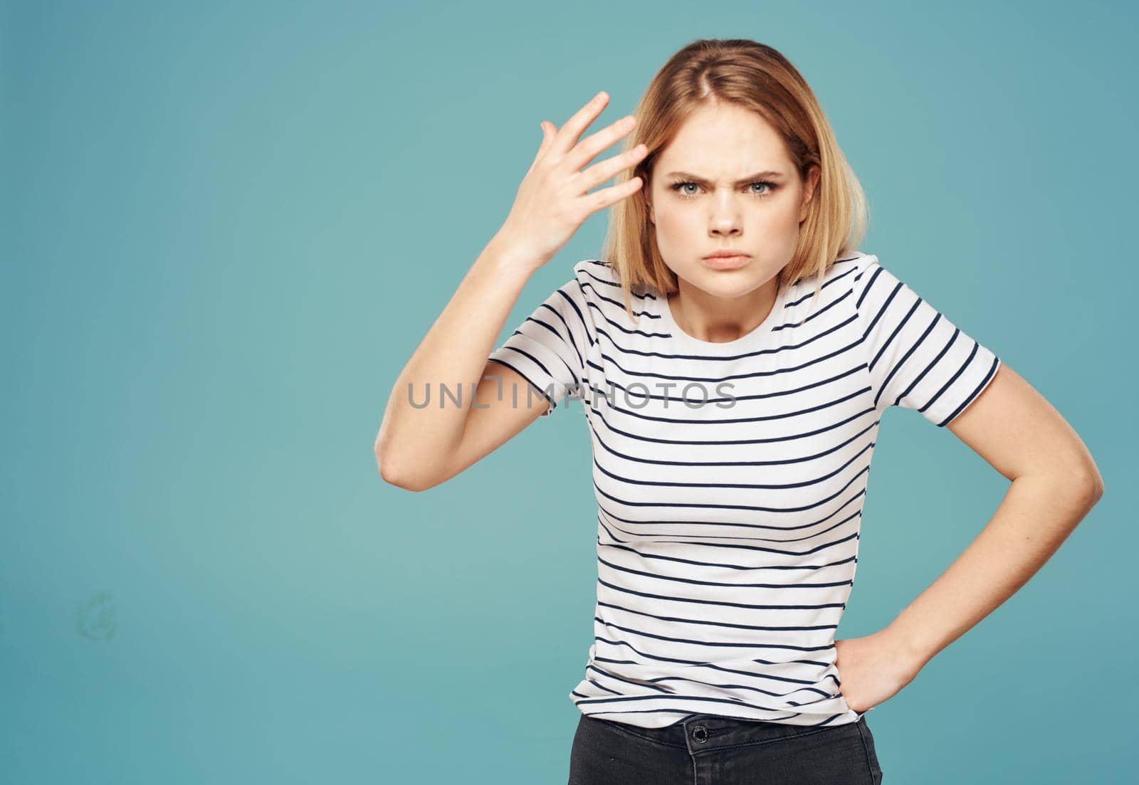 Nervous woman in a striped T-shirt gestures with her hands on a blue background. High quality photo