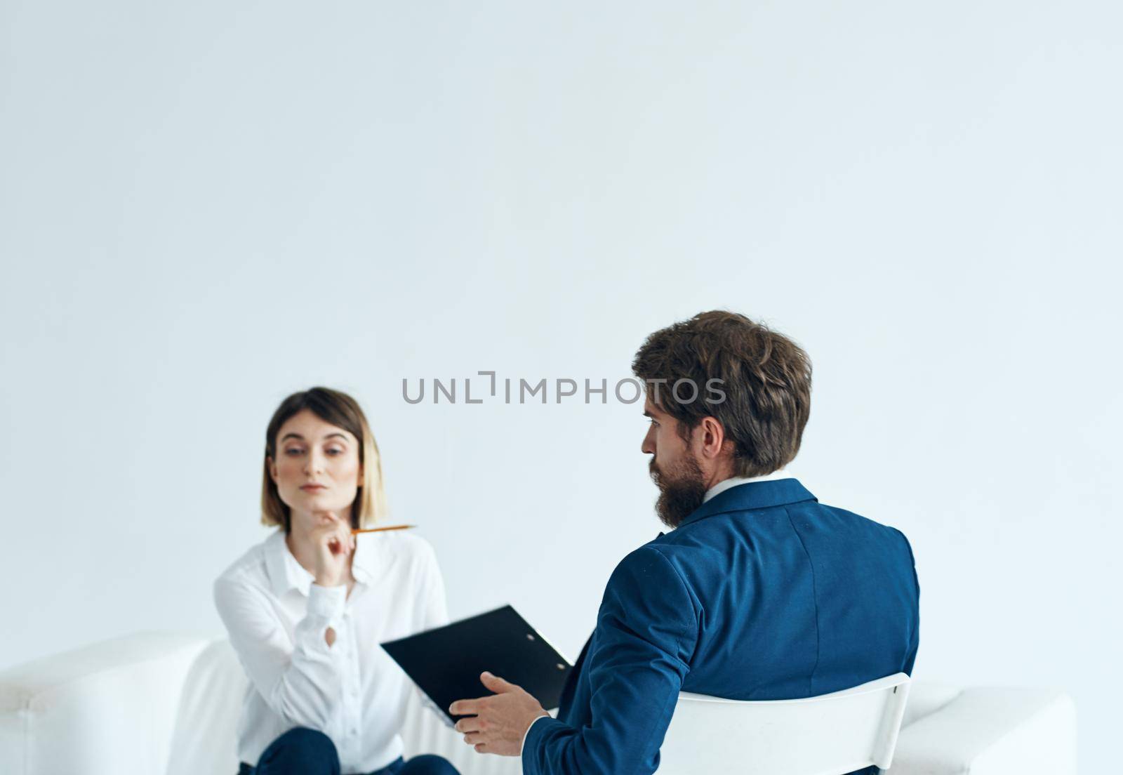 A woman psychologist with documents sits on the couch and a man on a chair in a suit. High quality photo