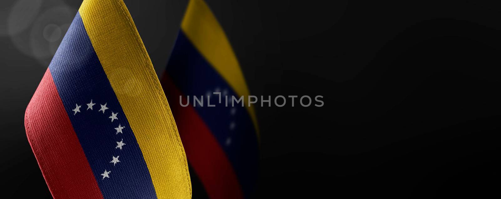 Small national flags of the Venezuela on a dark background.