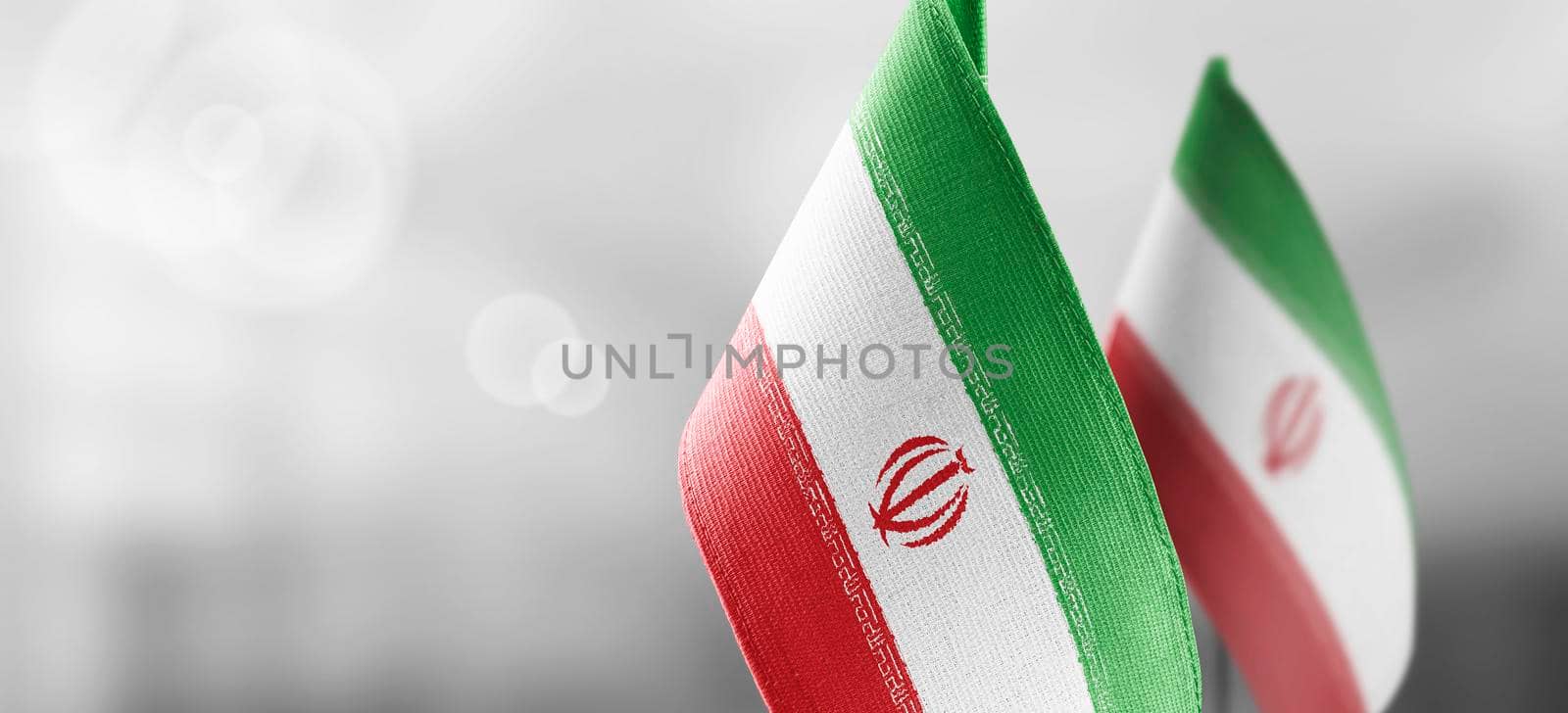 Small national flags of the Iran on a light blurry background.