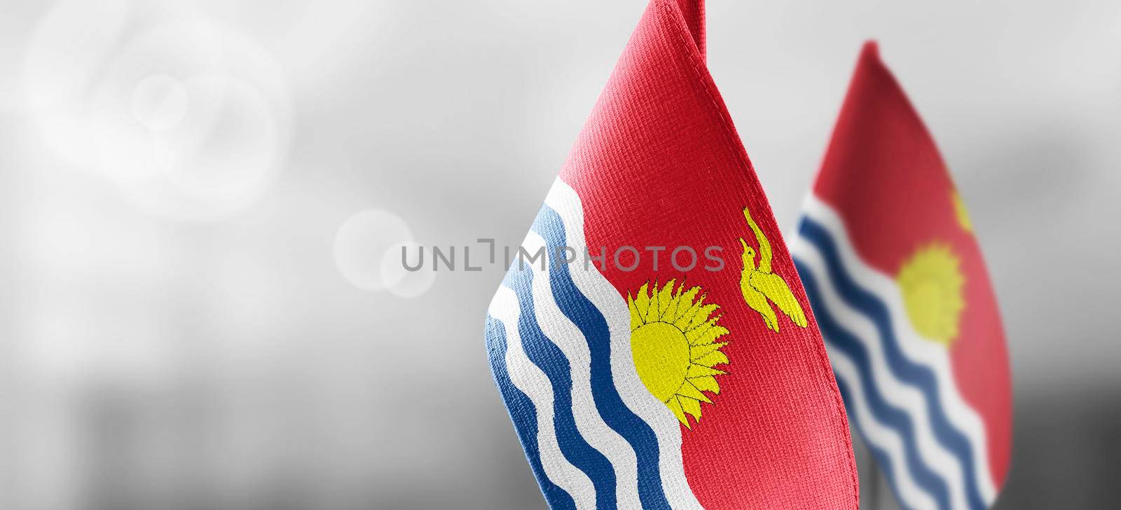 Small national flags of the Kiribati on a light blurry background.