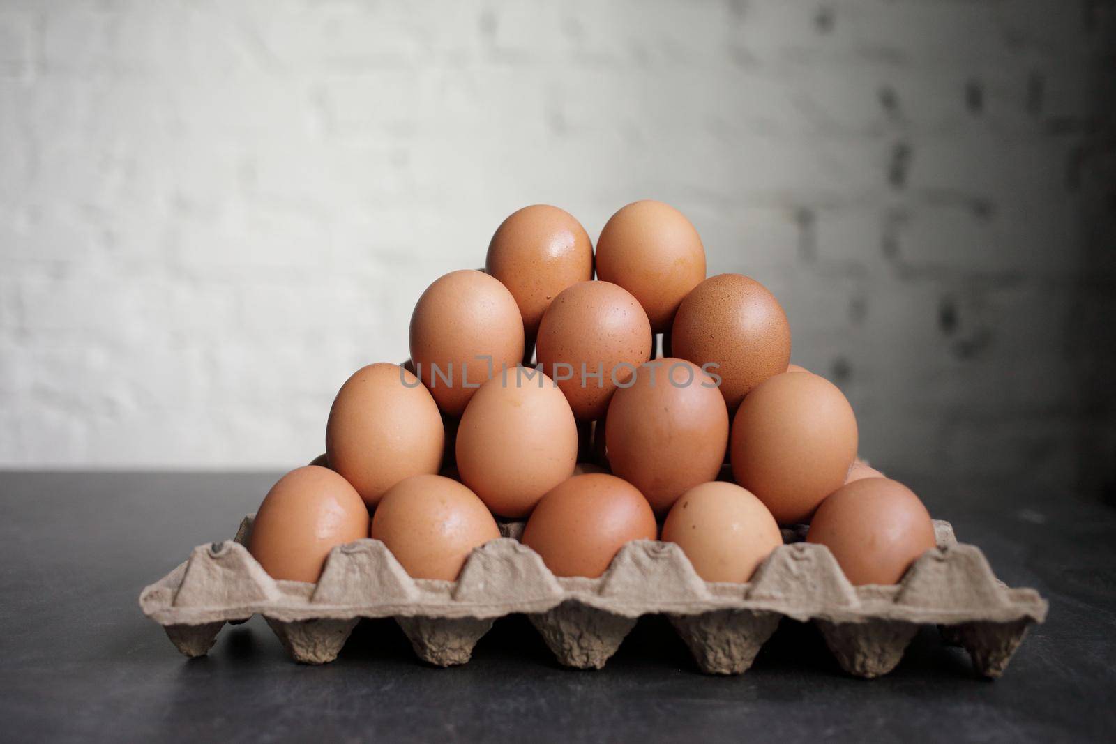 Pyramid of chicken eggs on a white wall background by selinsmo