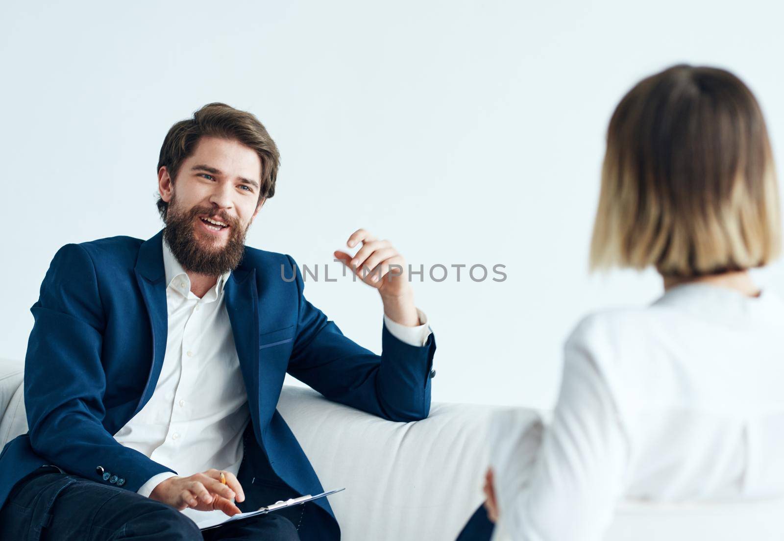 A man in a classic suit sits on the couch indoors with documents and a woman vacancies by SHOTPRIME