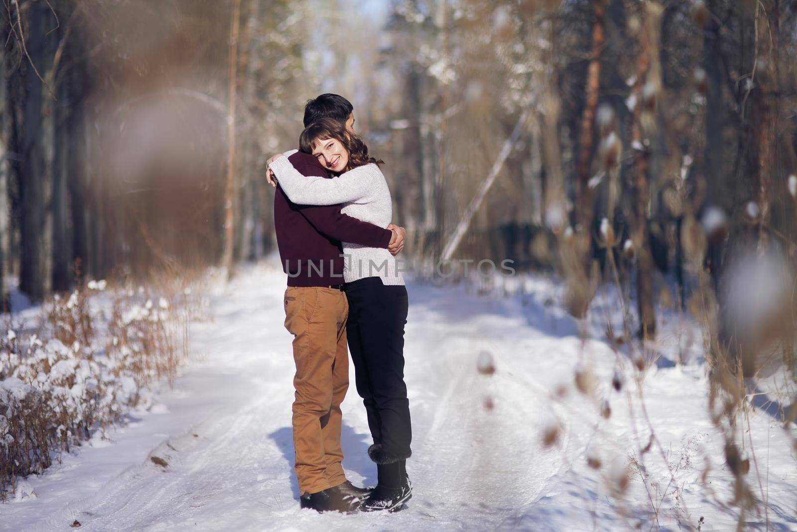 Young couple hug each other in winter in the park. Love story