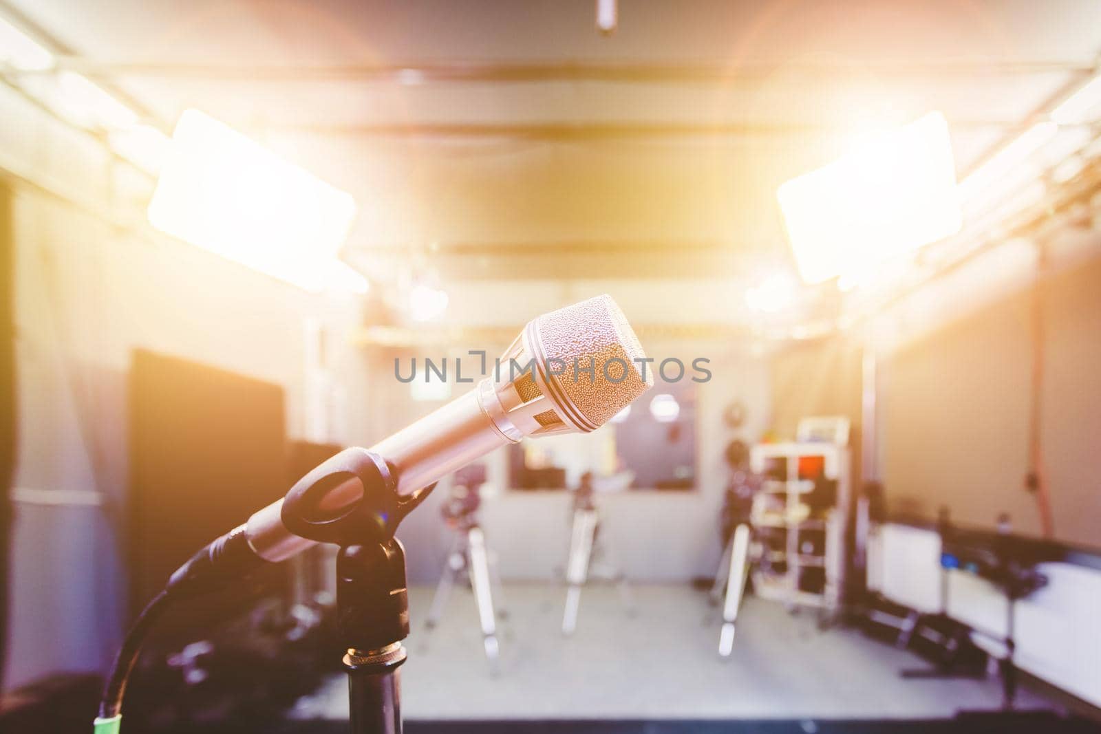 Professional microphone in recording tv studio, studio lights in blurry background