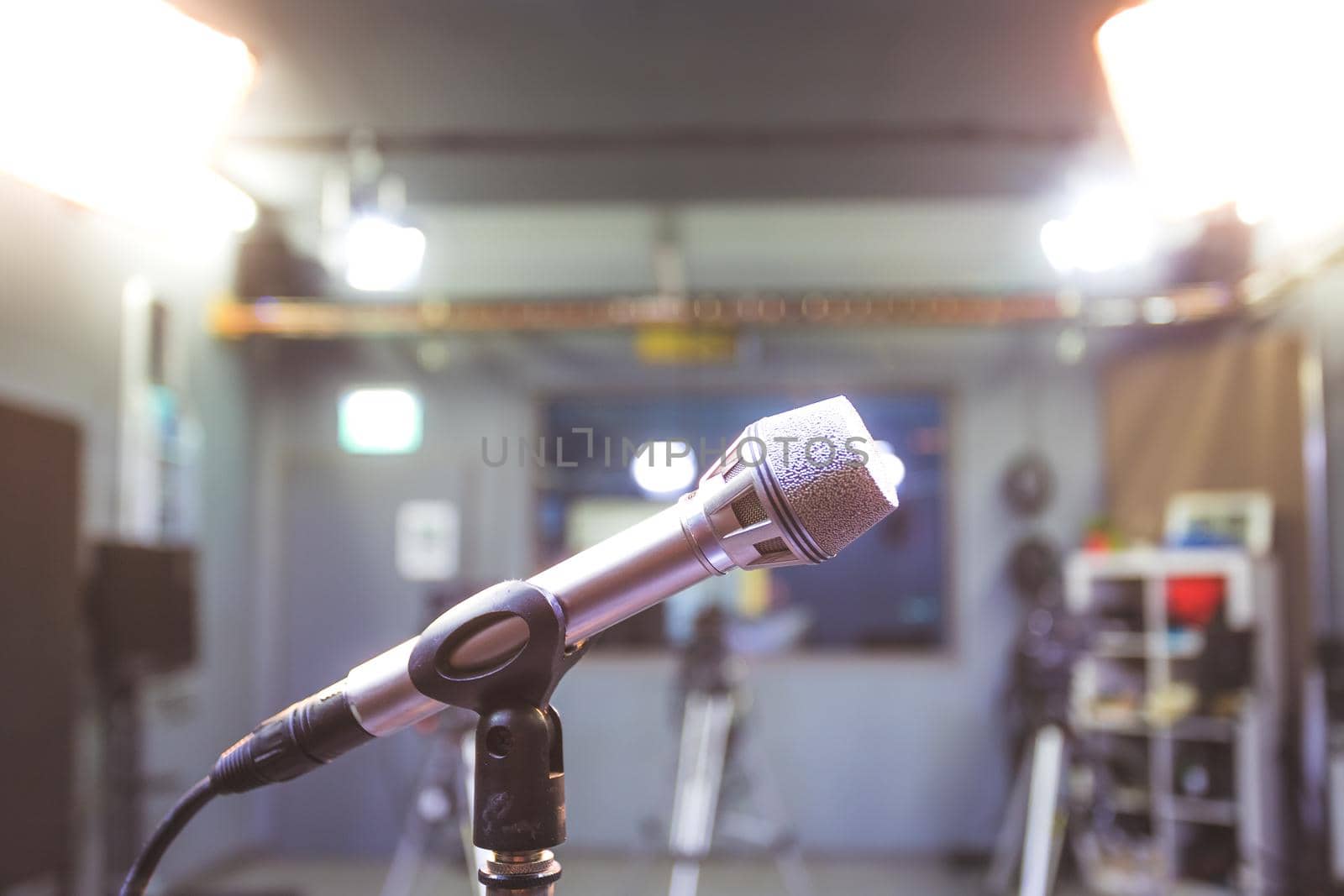Professional microphone in recording tv studio, studio lights in blurry background