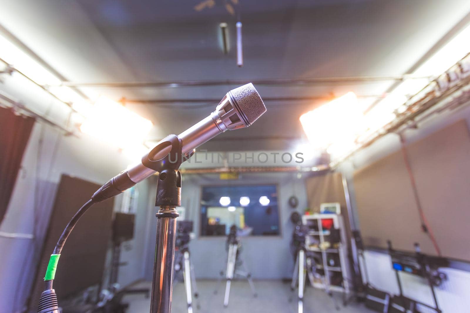 Professional microphone in recording tv studio, studio lights in blurry background