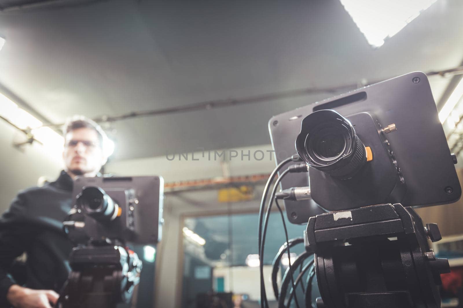 Male cameraman is operating a film camera in a television recording studio