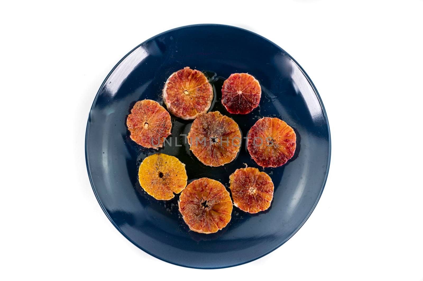 oranges seasoned with oil salt and pepper on a blue plate white background