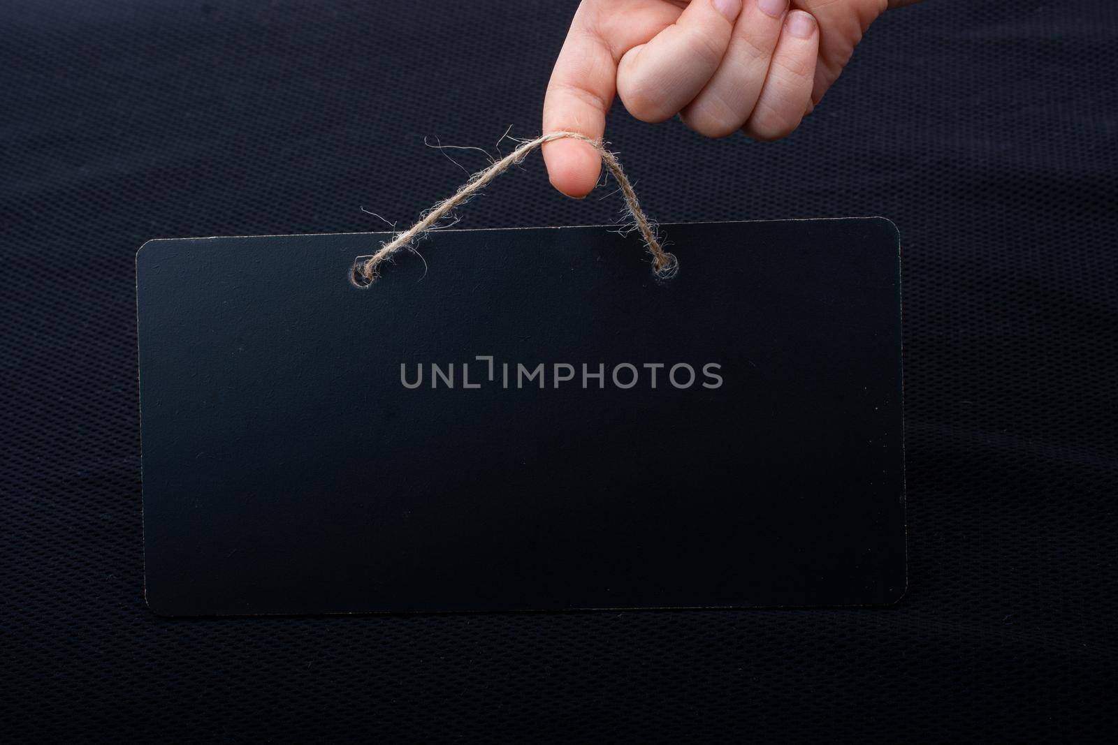 Rectangular shaped black notice board in hand on black background