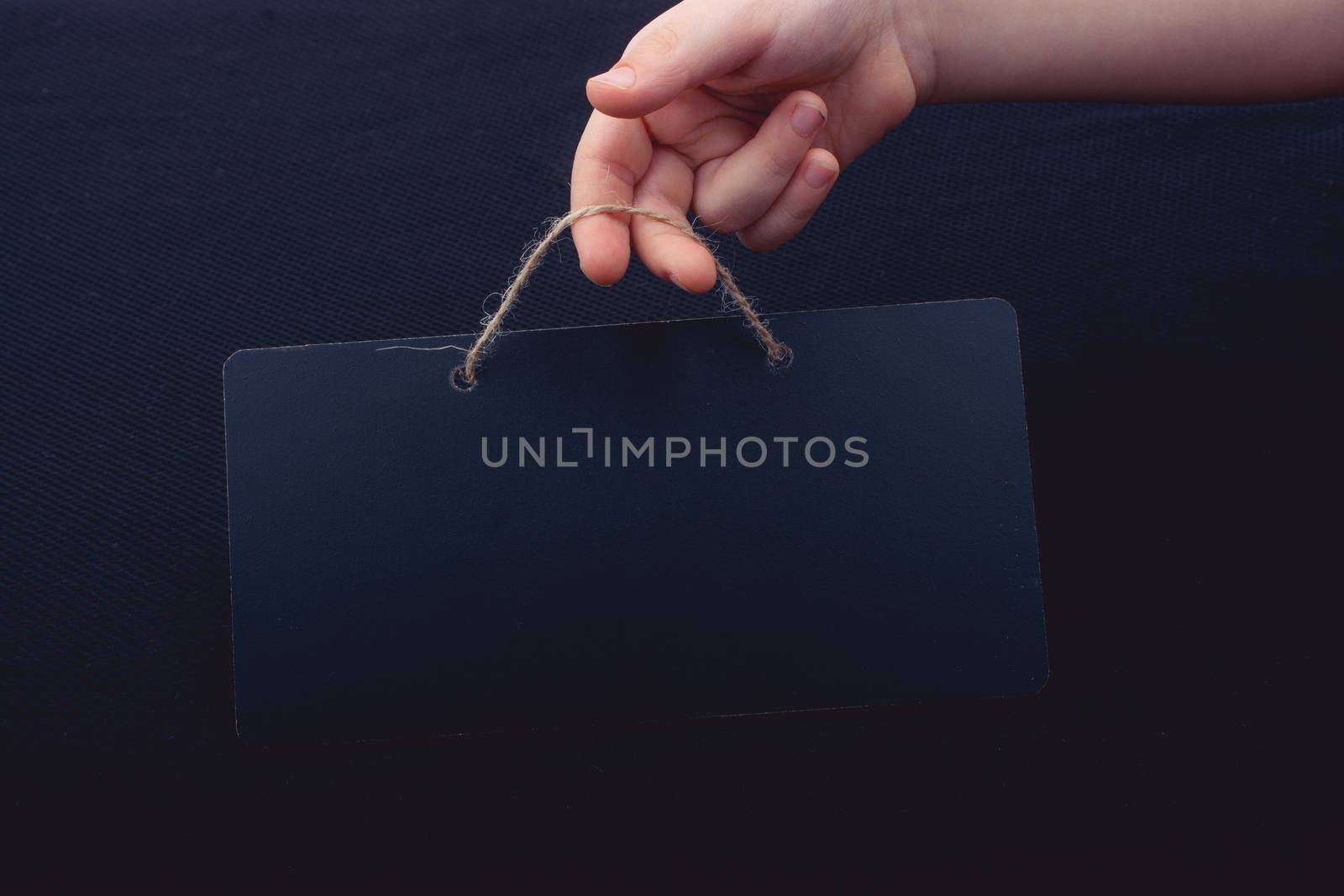 Rectangular shaped black notice board in hand on black background