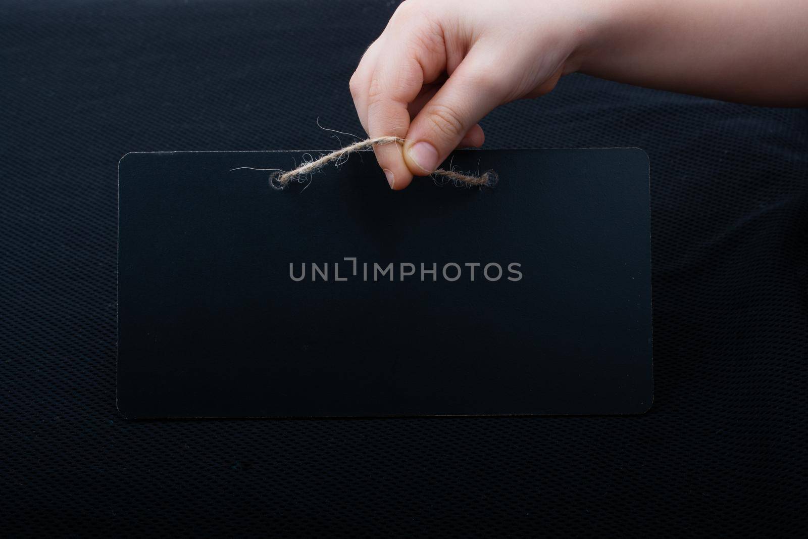 Rectangular shaped black notice board in hand on black background