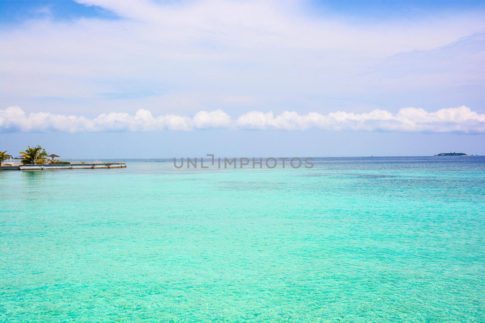 atoll of the tropics and maldives that are reflected in a sea of emerald with a cobalt blue sky